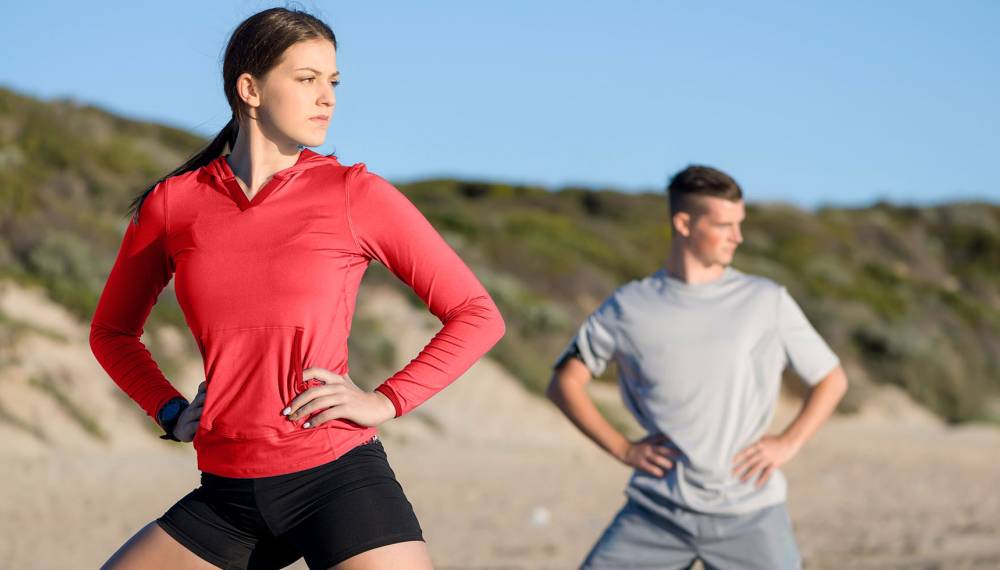 Zwei Sportler wärmen sich an einer Laufstrecke auf Sylt auf, mit Dünenlandschaft im Hintergrund