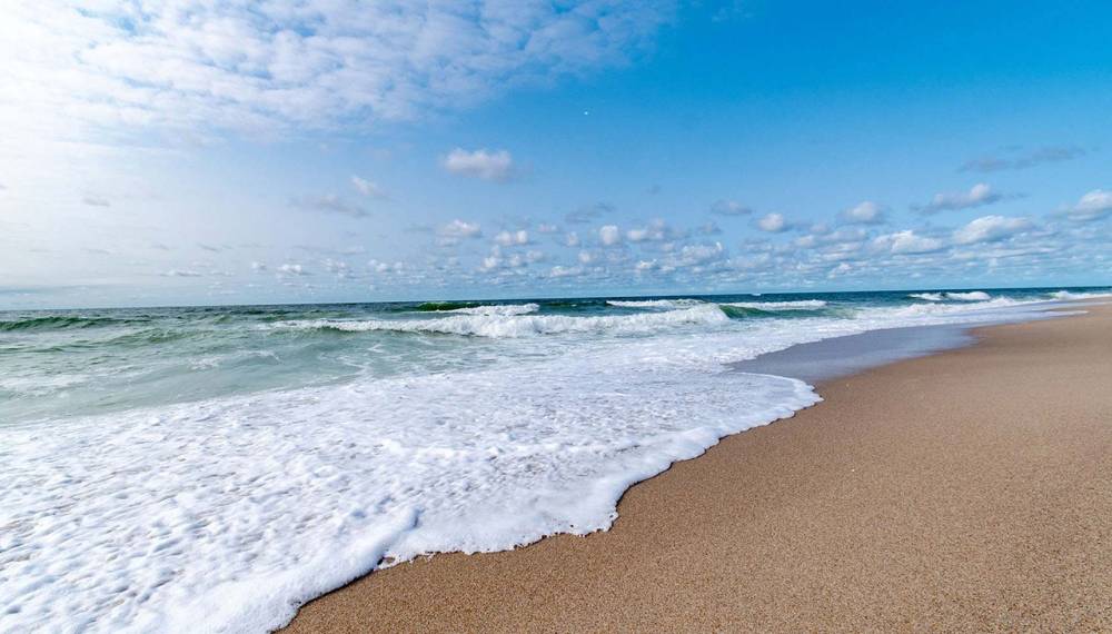 Weststrand auf Sylt mit sanften Wellen und weitem Himmel.