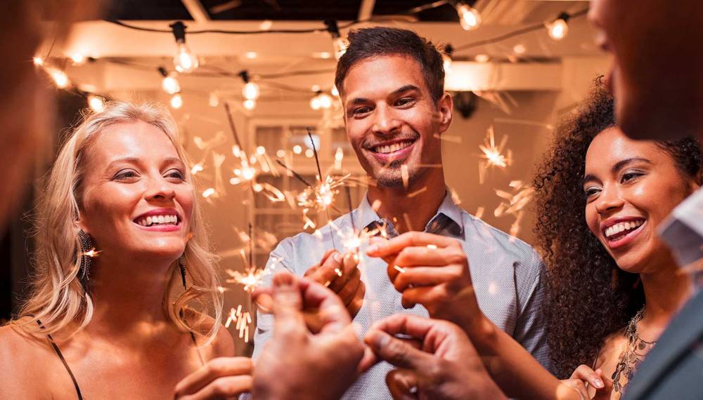 Gruppe von Freunden feiert mit Wunderkerzen Silvester.