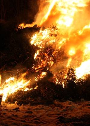 Biikebrennen an der Ostsee mit hohen Flammen und brennendem Reisighaufen in der Dunkelheit.