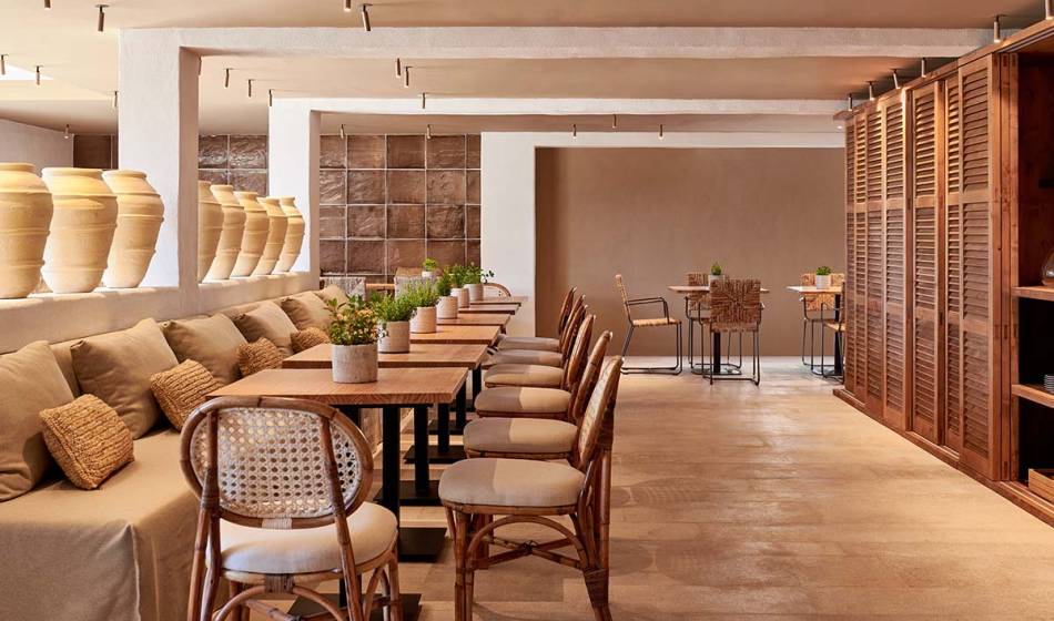 Elegant restaurant area with long wooden tables, comfortable upholstered seats and decorative elements in the Barefoot Hotel Mallorca.