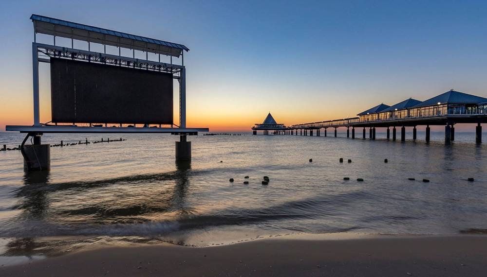 Eventstrand Heringsdorf mit großer Leinwand und Seebrücke bei Sonnenuntergang an der Ostsee.