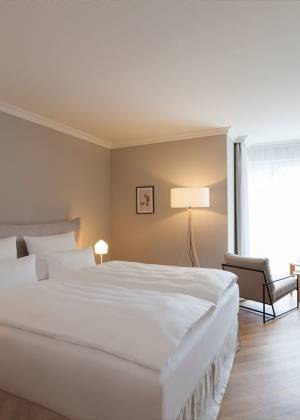 Modernes Hotelzimmer im Vju Hotel Rügen mit Doppelbett, Sesseln und Fernseher.
