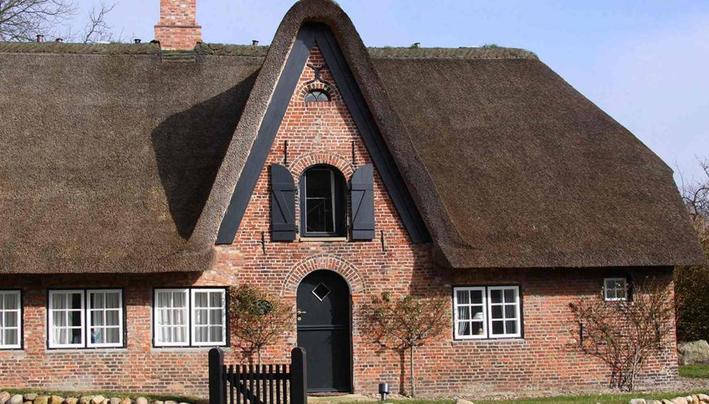 Friesenhaus mit Reetdach und roter Backsteinfassade auf Sylt.