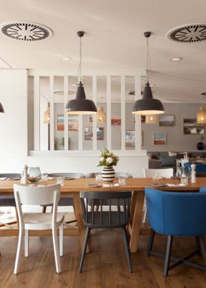 Stilvoll eingerichteter Essbereich in der KITCHEN.BAR im Wyn. Strandhotel auf Sylt mit farbigen Stühlen und viel Tageslicht.