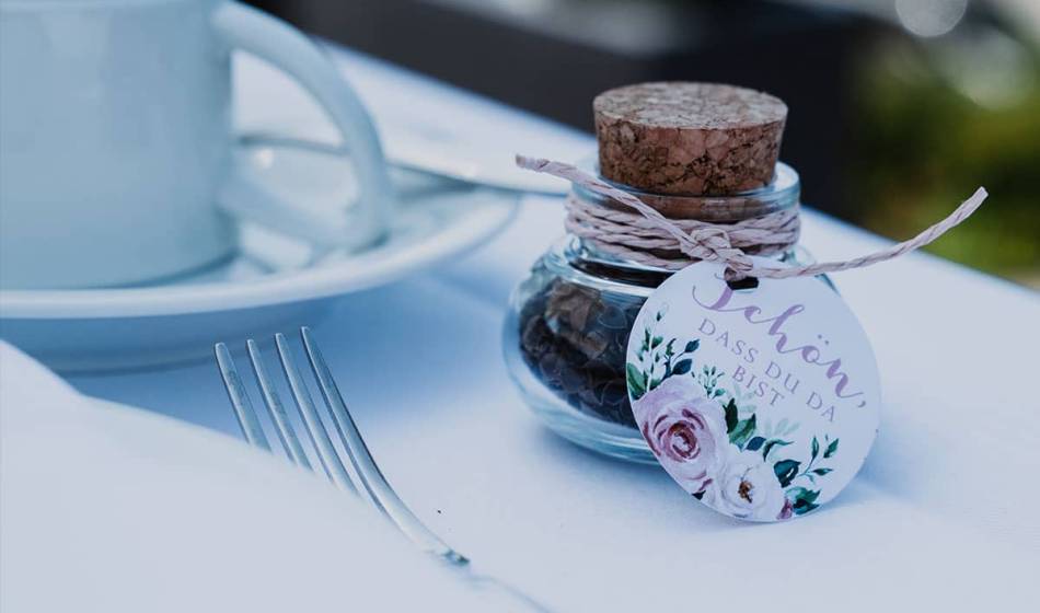 Wedding favor in the form of a decorative glass with a personal tag and cork stopper.
