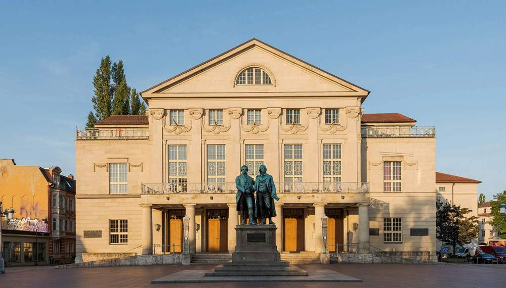 Deutsches Nationaltheater Weimar mit klassizistischer Fassade und Goethe-Schiller-Denkmal auf dem Theaterplatz.