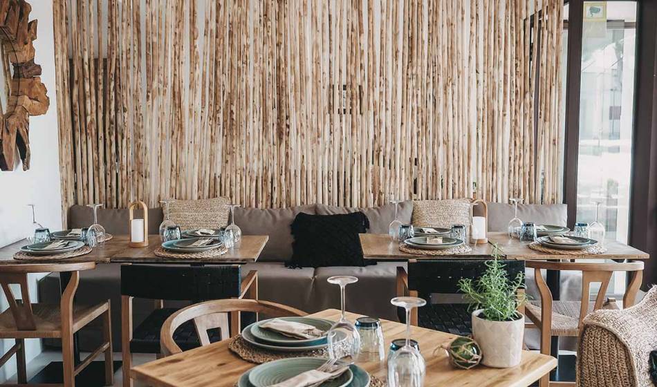 Dining area with decorative wooden tables, set plates and modern elements in a cozy room at the Barefoot Hotel Mallorca.