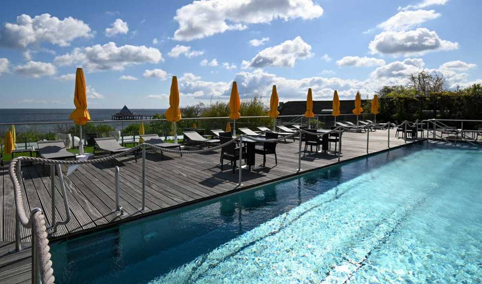 Poolterrasse im Sonnengarten des Hotel Kaiserhof Heringsdorf mit Meerblick, Liegestühlen und Sonnenschirmen.
