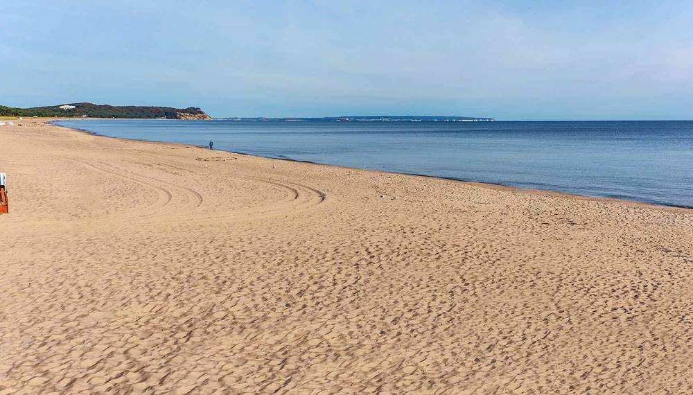 Weiter Sandstrand bei Göhren auf Rügen mit Strandkörben und Blick auf die Ostsee bei ruhigem Wetter.