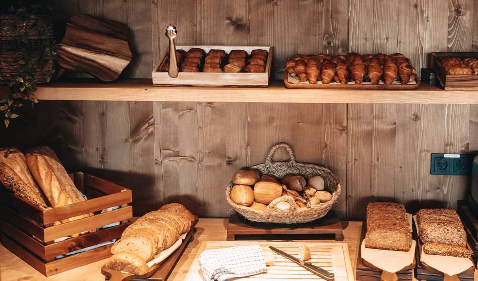 Various breads, rolls and croissants are displayed on a rustic wooden shelf for breakfast at the Barefoot Hotel Mallorca.