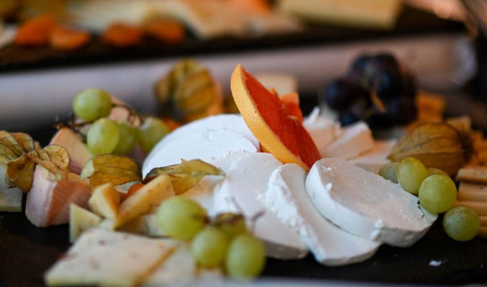 Various types of cheese are lovingly arranged on a slate platter with fresh fruit in the Strandläufer restaurant on Rügen.