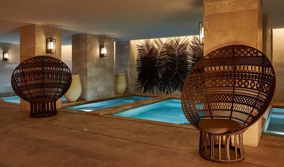 Wellnessbereich mit beheiztem Innenpool, modernen Lichtelementen und gemütlichen Sitzgelegenheiten im Barefoot Hotel.