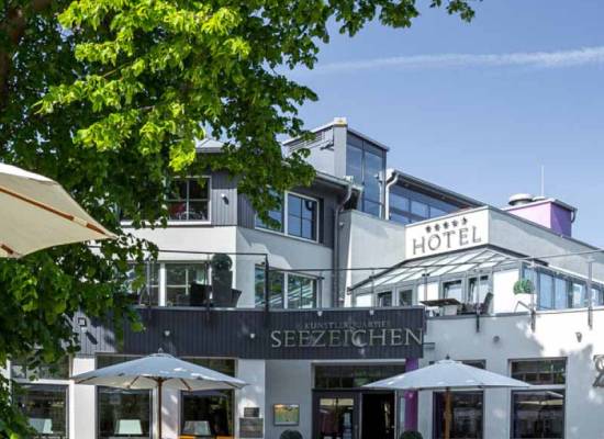 Sonnige Terrasse des Künstlerquartiers Seezeichen in Ahrenshoop mit Sitzgelegenheiten und grüner Umgebung.