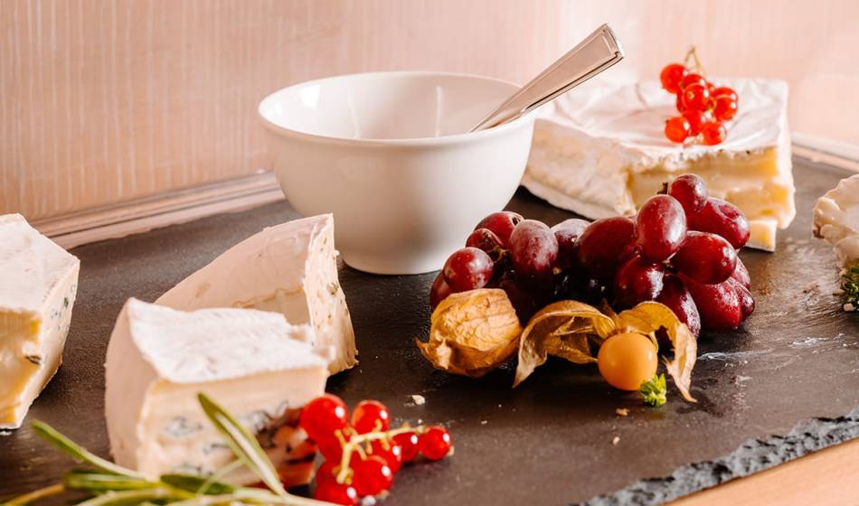 A cheese platter with soft cheese, grapes, currants and physalis on a slate plate at the Künstlerquartier Seezeichen.