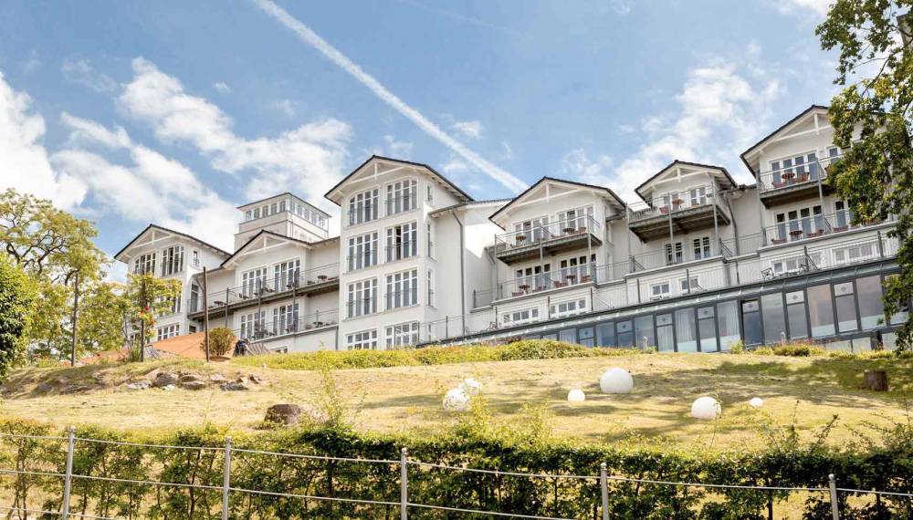 Außenansicht des Vju Hotels Rügen in Göhren mit großzügigen Balkonen und einer gepflegten Grünanlage im Vordergrund.