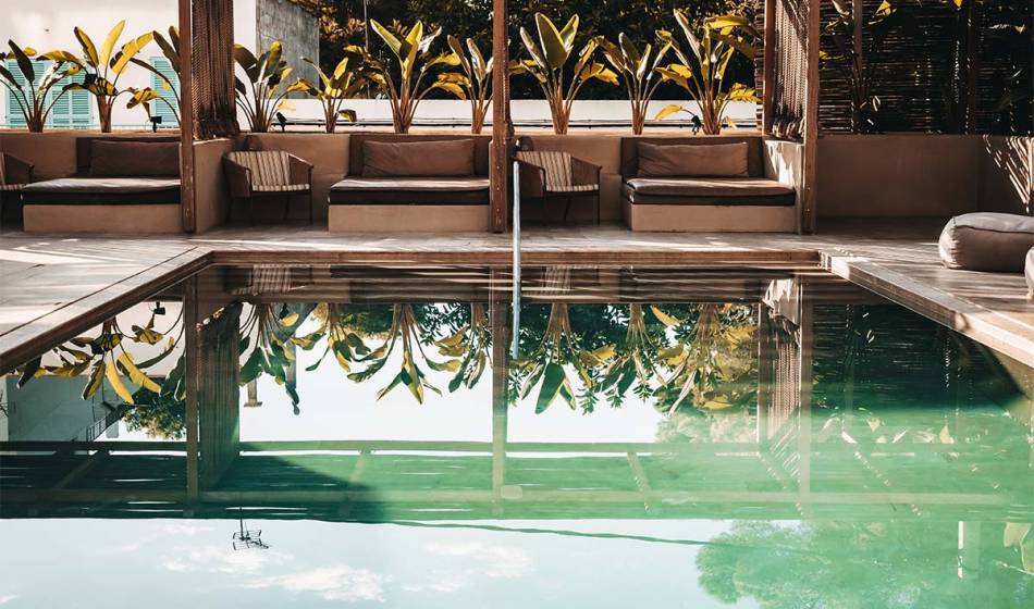 Außenbereich mit Pool, umgeben von Palmen und Liegen im Wellnessbereich des Barefoot Hotels Mallorca.