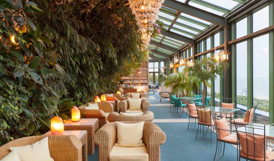 Cozy rattan furniture surrounded by plants and large windows in the winter garden of the Kaiserhof Heringsdorf on Usedom.