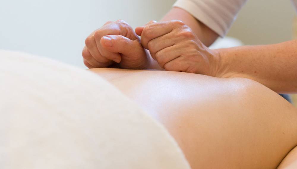 Nahaufnahme einer Massage im Day Spa, bei der kräftige Handgriffe auf dem Rücken angewendet werden.