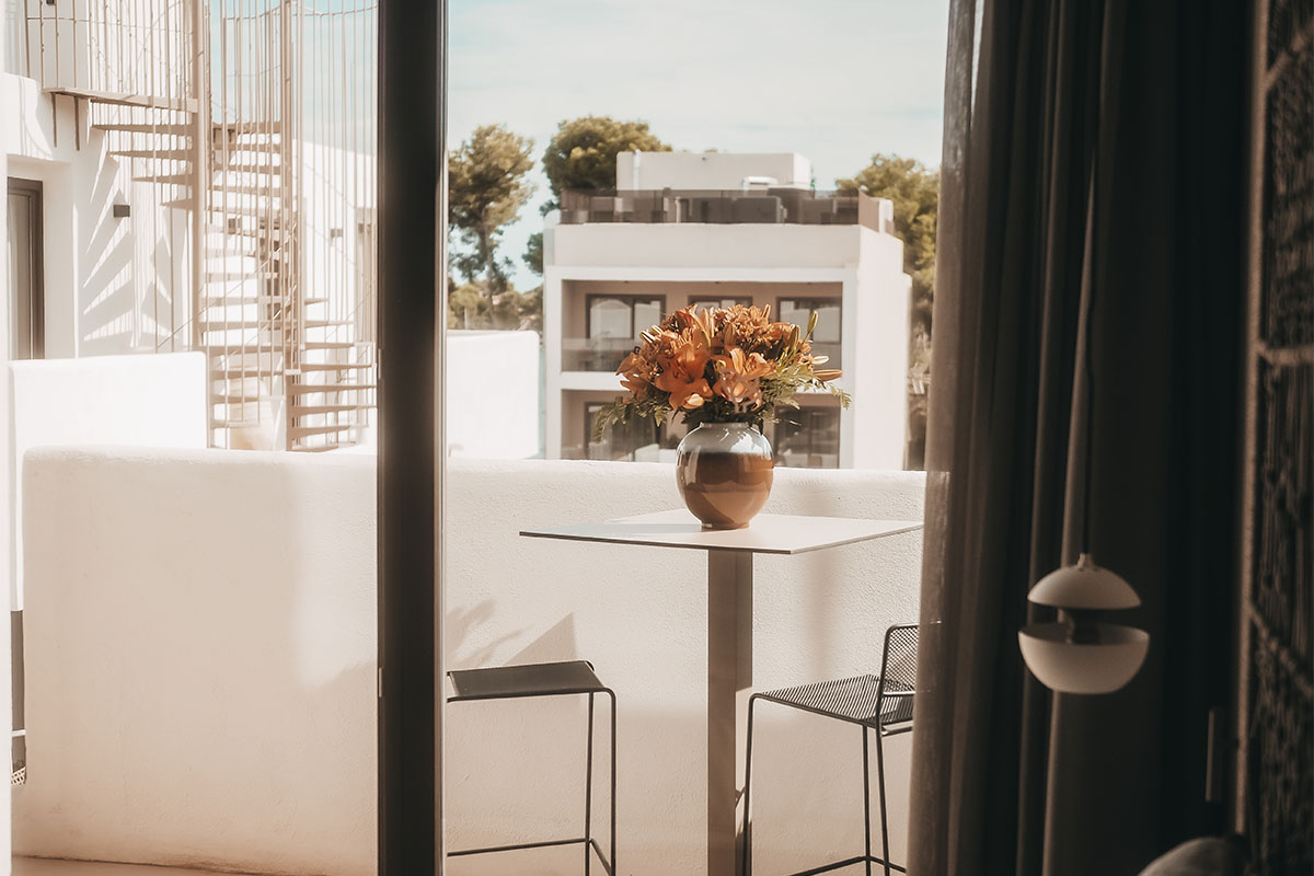 Elegante balcón de la Pequeña Suite con mesa, jarrón de flores y vistas al Hotel Descalzos de Mallorca.
