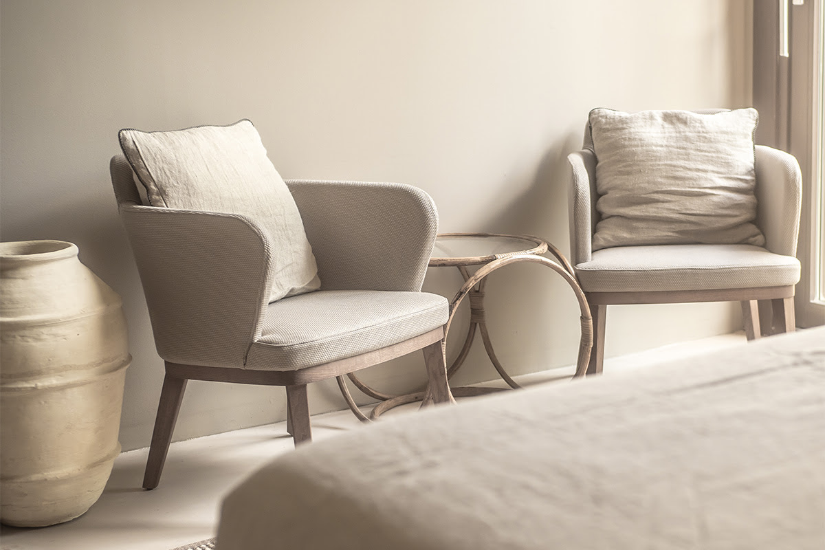 Acogedora zona de estar con dos sillones, cojines y mesa auxiliar en la Pequeña Suite del Hotel Barefoot Mallorca.