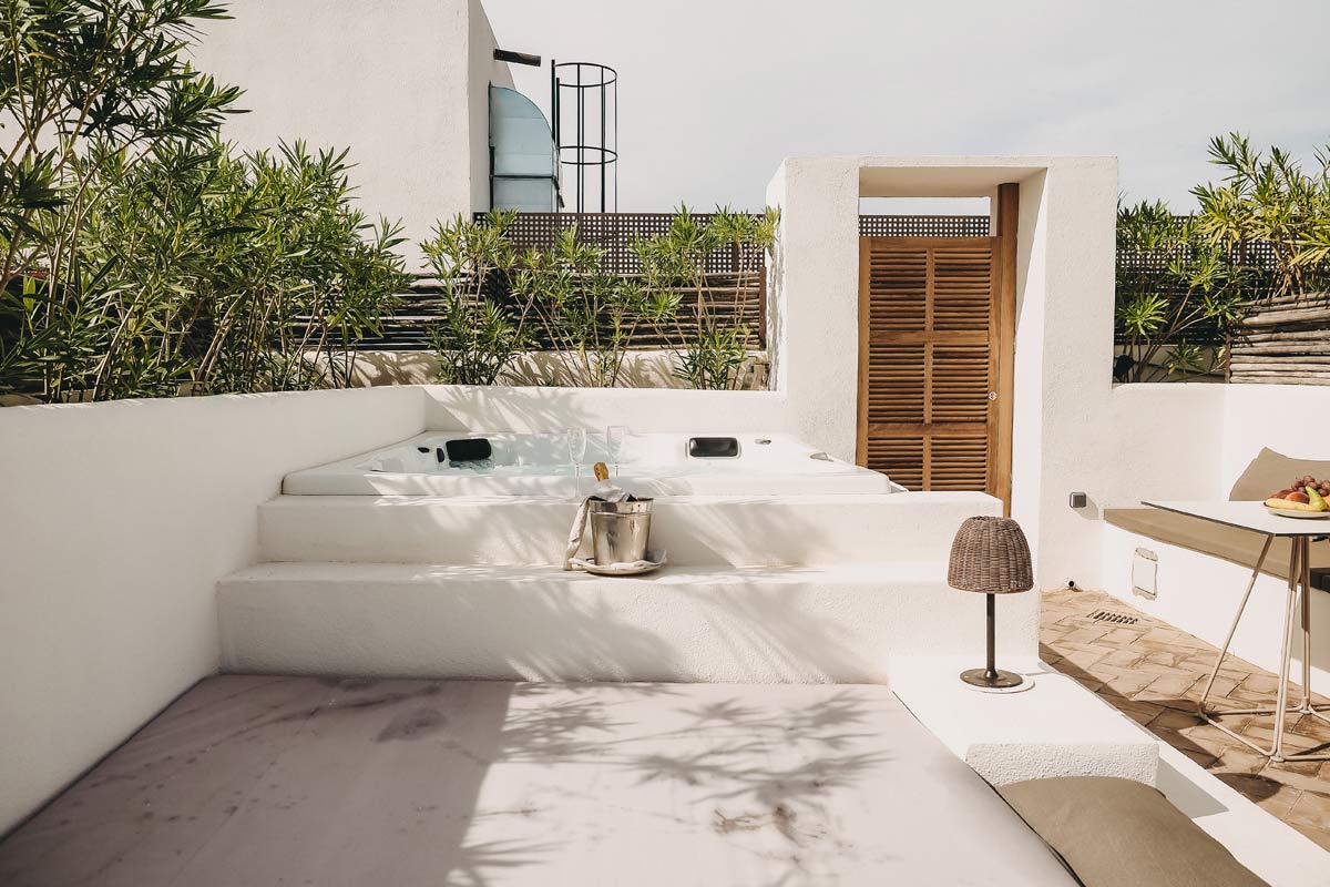 Terraza privada de la Pequeña Suite con bañera de hidromasaje, zona de estar y ambiente mediterráneo en el Barefoot Hotel Mallorca.