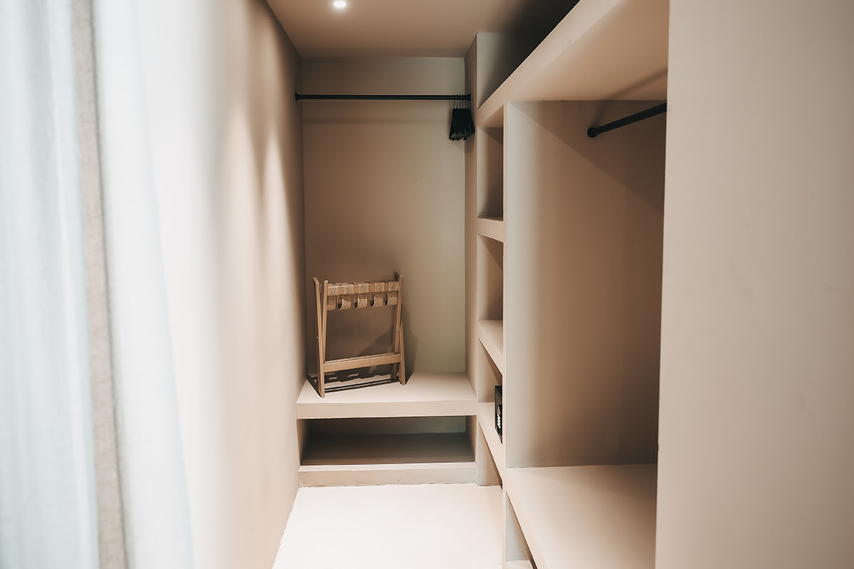 Offener Ankleidebereich der Suite Patio des Barefoot Hotel auf Mallorca mit Regalfächern, Kleiderstange und hellem Design