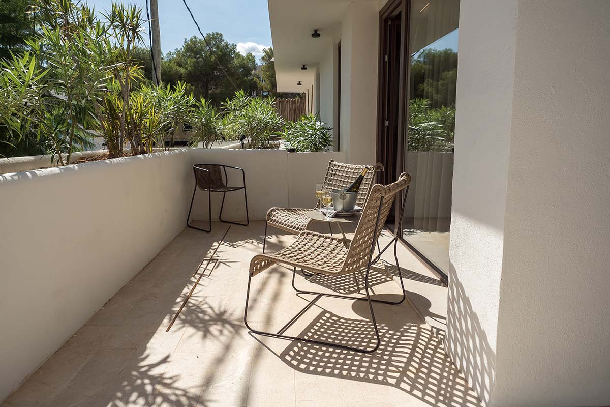 Sonnige Terrasse der Suite Patio im Barefoot Hotel auf Mallorca mit eleganten Möbeln und Blick auf Pflanzen.