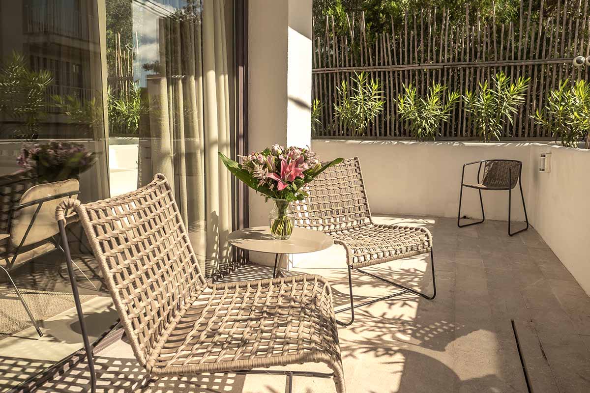 Gemütliche Terrasse der Suite Patio im Barefoot Hotel Mallorca mit eleganten Stühlen, Tisch und einem Blumenarrangement