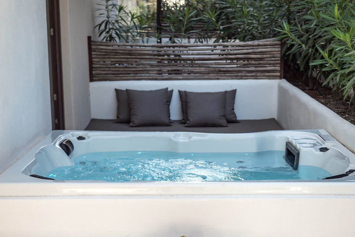 Privater Whirlpool auf der Terrasse der Suite Patio im Barefoot Hotel Mallorca mit Kissen und umgeben von Pflanzen