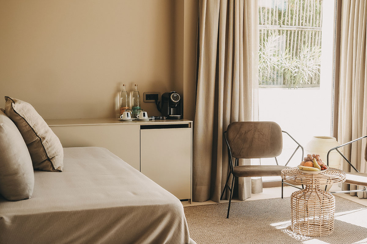 Gemütlicher Wohnbereich in der Suite Patio des Barefoot Hotel auf Mallorca mit Sitzmöbeln, Tisch und Blick ins Grüne