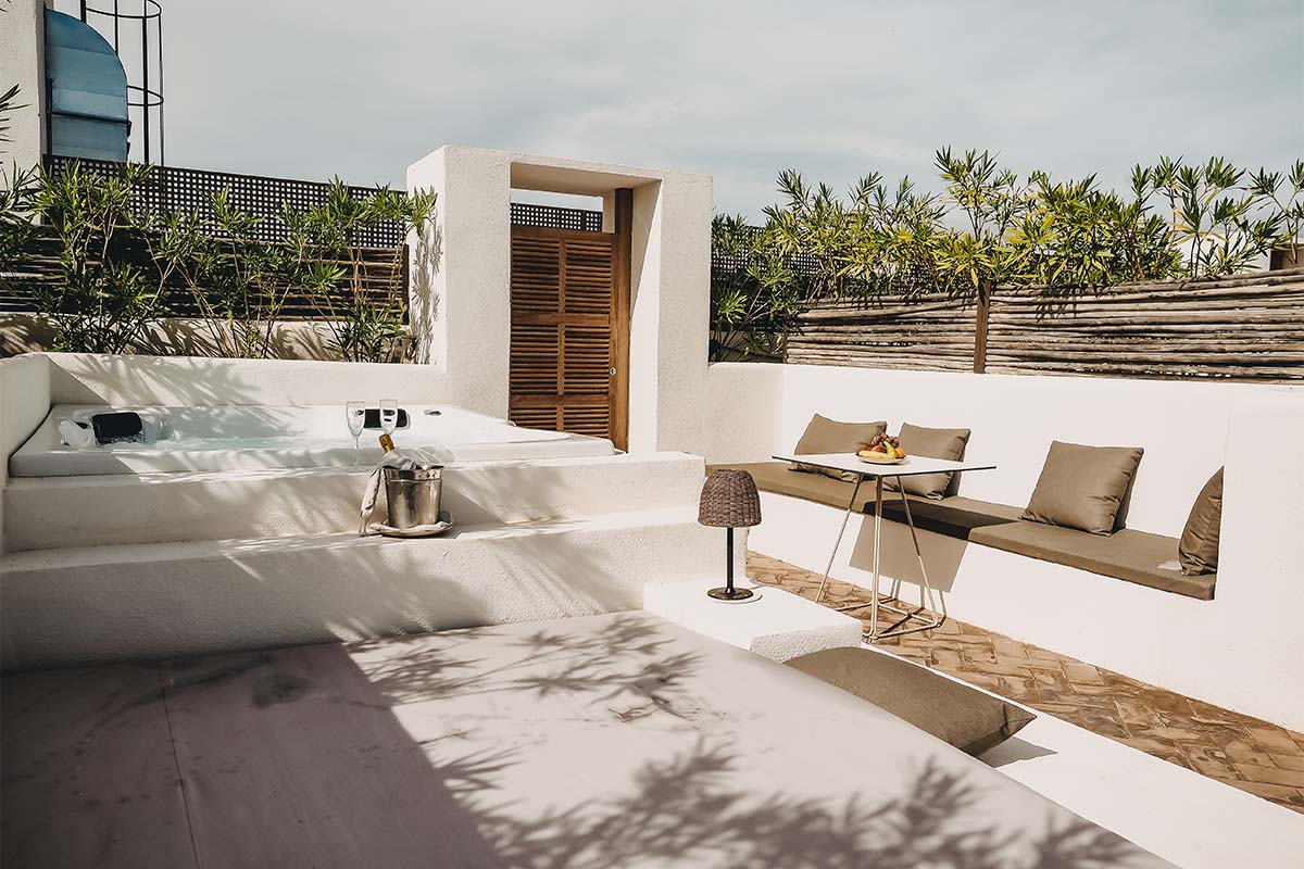 Privater Außenbereich mit Whirlpool, Sitzgelegenheit und Tisch auf der Terrasse einer Suite im Barefoot Hotel Mallorca.