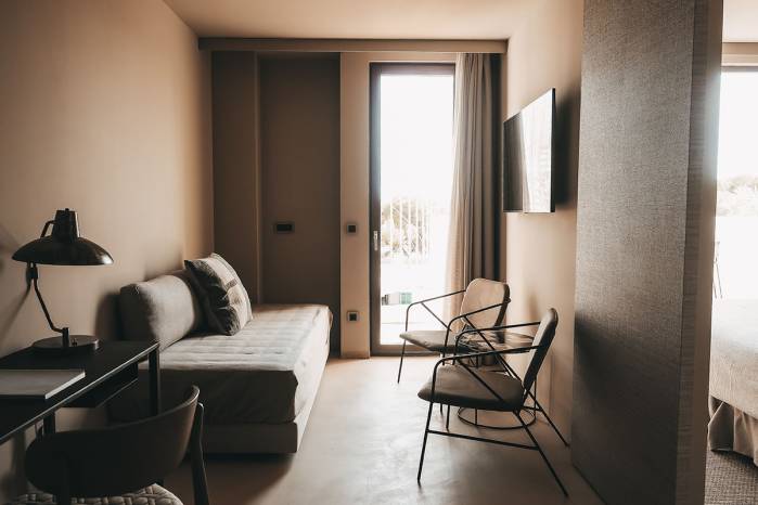 Modern eingerichteter Wohnbereich in der Lado Campo Suite im Barefoot Hotel mit einem Sofa, zwei Sesseln und  Blick auf die Terrasse.