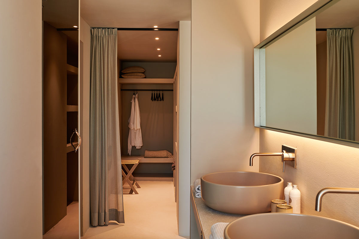 Elegante Ankleide mit Vorhang und stilvollem Badezimmer mit Doppelwaschbecken in der Suite des Barefoot Hotels auf Mallorca.