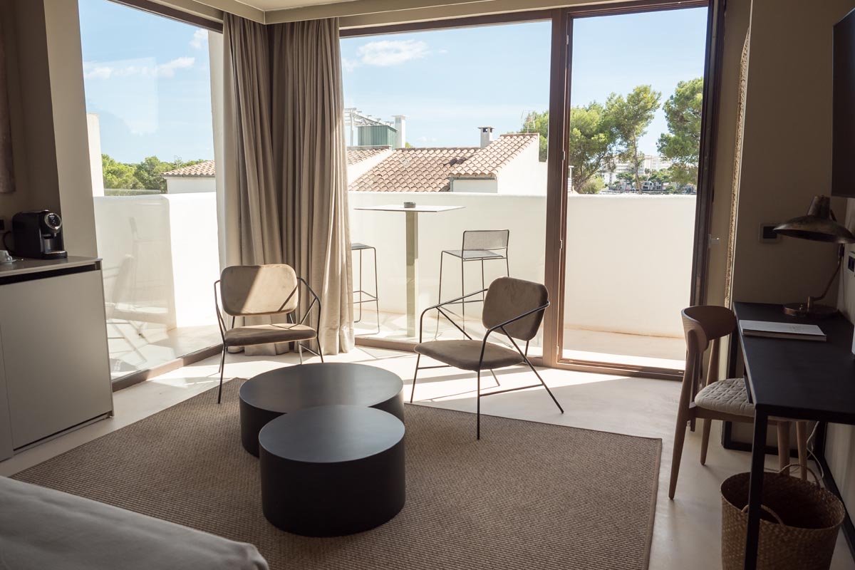 Innenansicht einer Suite im Barefoot Hotel Mallorca mit großen Fenstern, Sitzbereich und Blick auf die Umgebung.