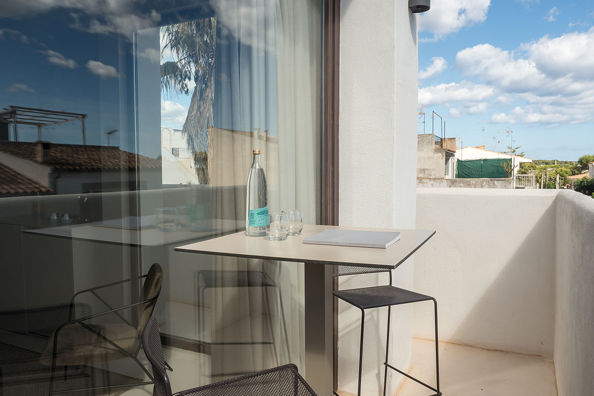 Moderner Balkon der Suite mit Tisch, Stühlen und Blick auf die umliegenden Gebäude des Barefoot Hotels auf Mallorca.