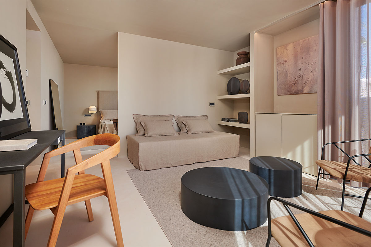 Moderner Wohnbereich der Suite im Barefoot Hotel auf Mallorca mit Sofa, Holzstuhl und stilvollen Details.