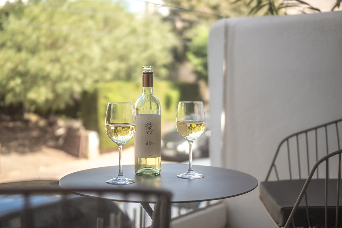 Flasche Weißwein mit zwei gefüllten Gläsern auf einem Tisch auf der Terrasse des Doppelzimmers Puerto im Barefoot Hotel Mallorca