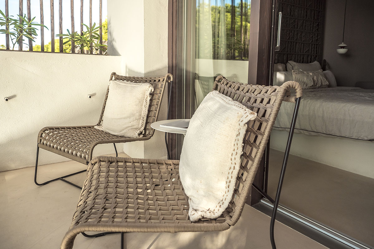 rivater Balkon im Doppelzimmer Mar des Barefoot Hotel Mallorca mit zwei stilvollen Stühlen, Kissen und einem kleinen Tisch.