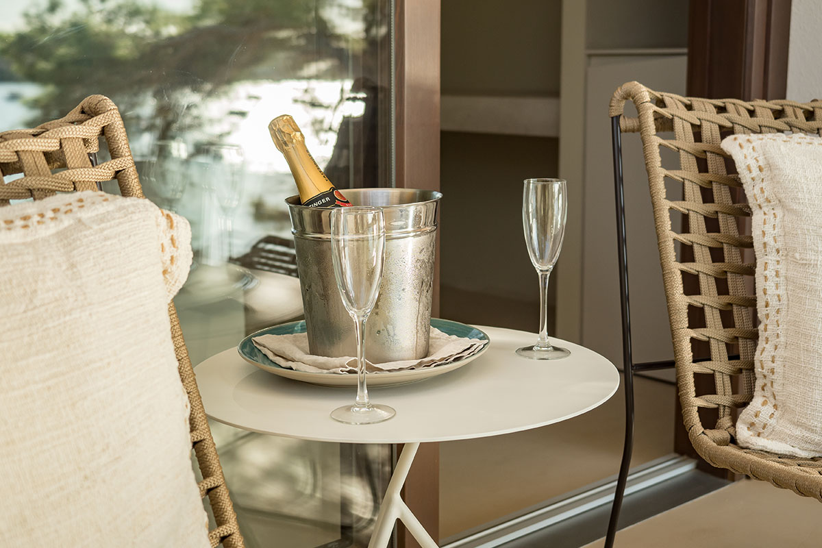 Champagnerflasche in einem Kühler mit zwei Gläsern auf einem Tisch auf der Terrasse des Doppelzimmers Mar im Barefoot Hotel Mallorca.