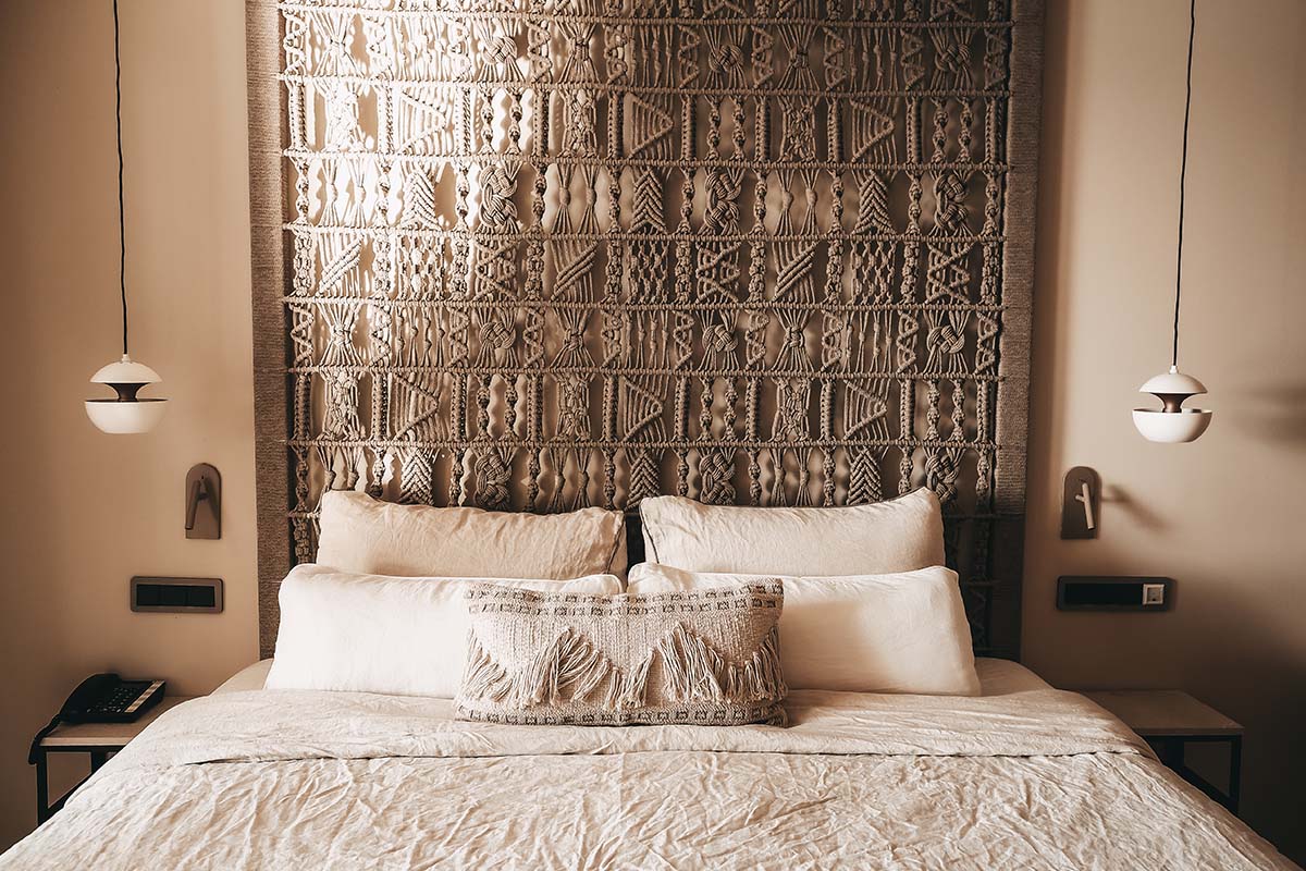 Schlafbereich im Doppelzimmer Mar des Barefoot Hotel Mallorca mit großem Bett, dekorativem Kopfteil und eleganter Beleuchtung.