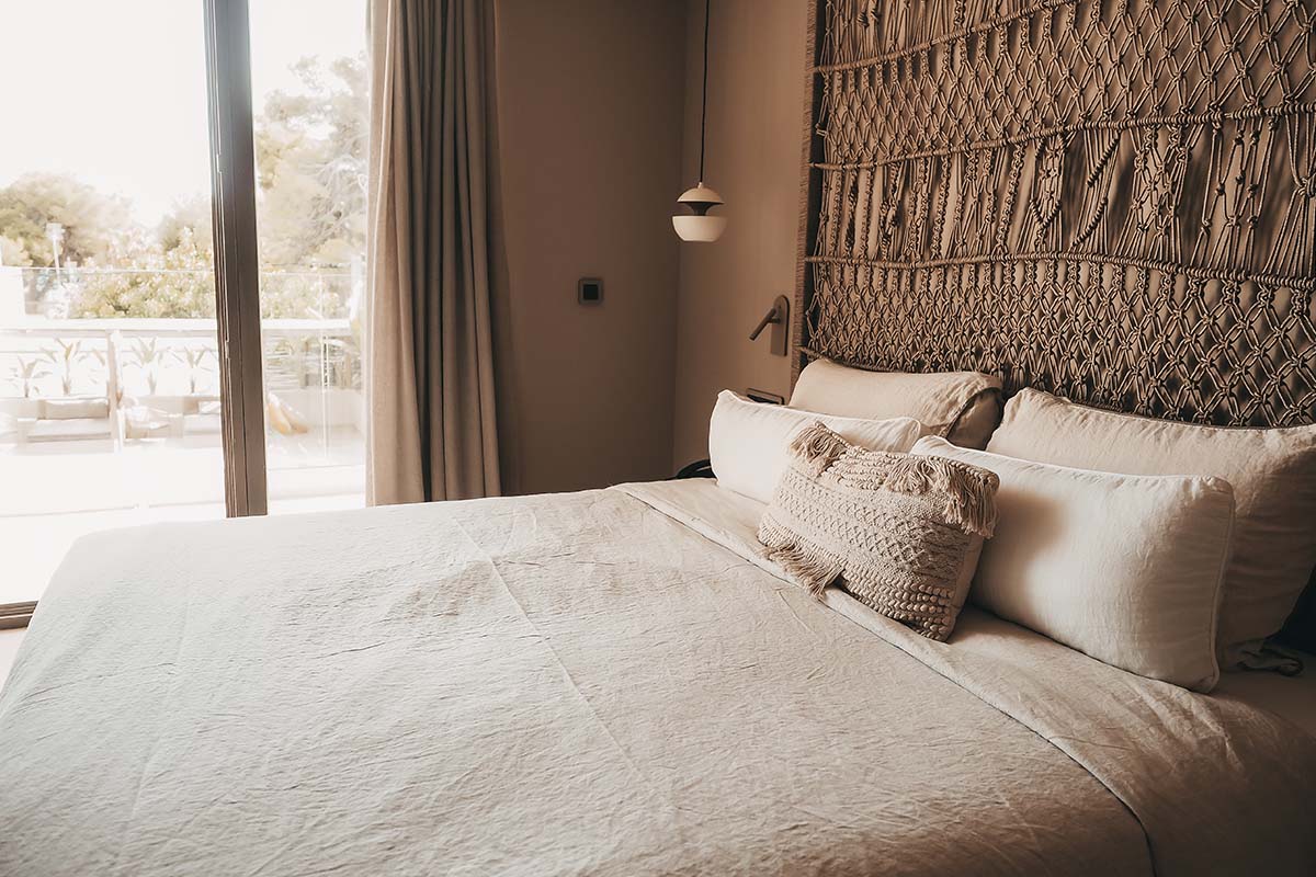 Großes Doppelbett im Deluxe Doppelzimmer Oasis des Barefoot Hotel Mallorca mit dekorativem Kopfteil, weichen Kissen und Balkonblick.