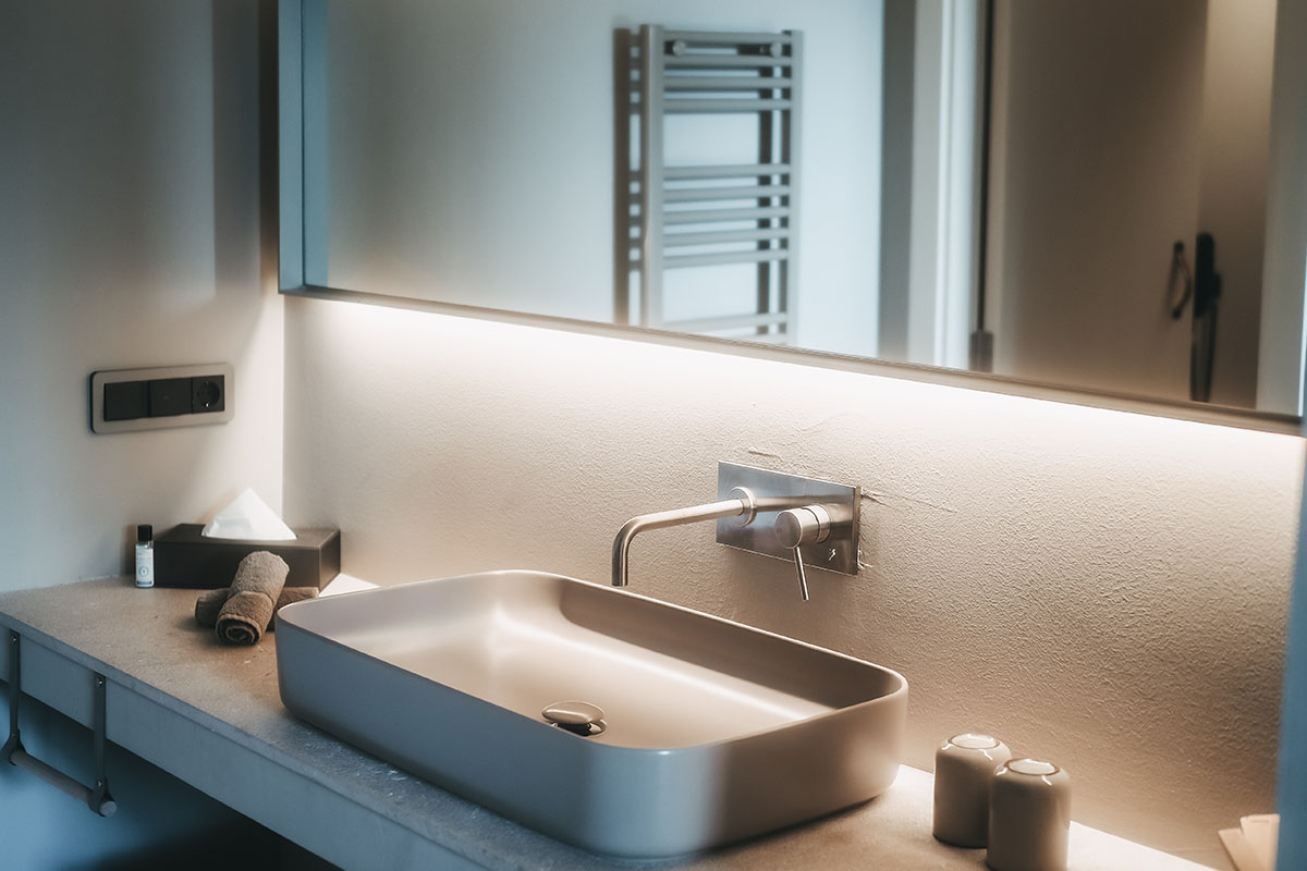 Waschbecken im Doppelzimmer Oasis des Barefoot Hotel auf Mallorca mit modernem Design, großem Spiegel und eleganter Beleuchtung.