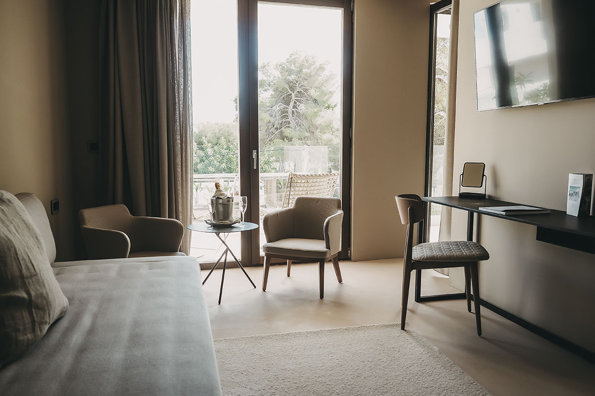 Wohnbereich im Deluxe Doppelzimmer Oasis des Barefoot Hotel auf Mallorca mit Sofa, Sesseln, Schreibtisch und Zugang zum Balkon.