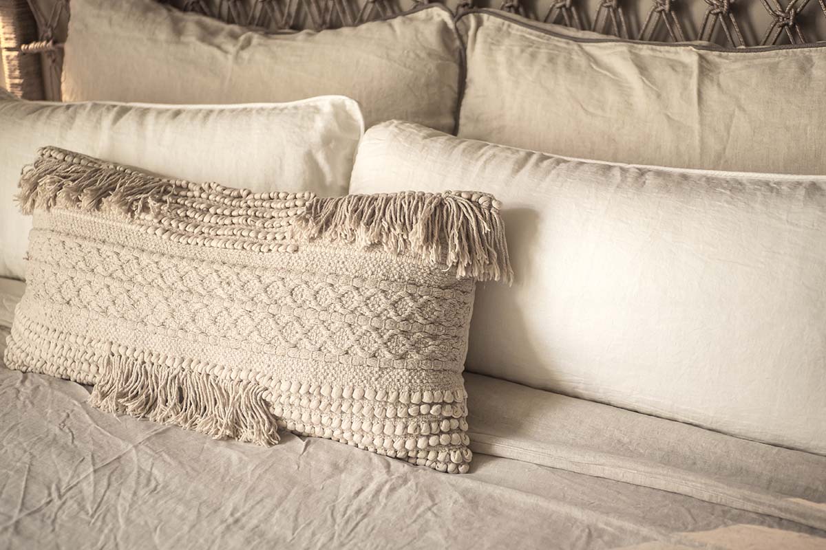 Strukturiertes Kissen aus Naturmaterialien auf einem Bett im Barefoot Hotel Mallorca für entspanntes Ambient.