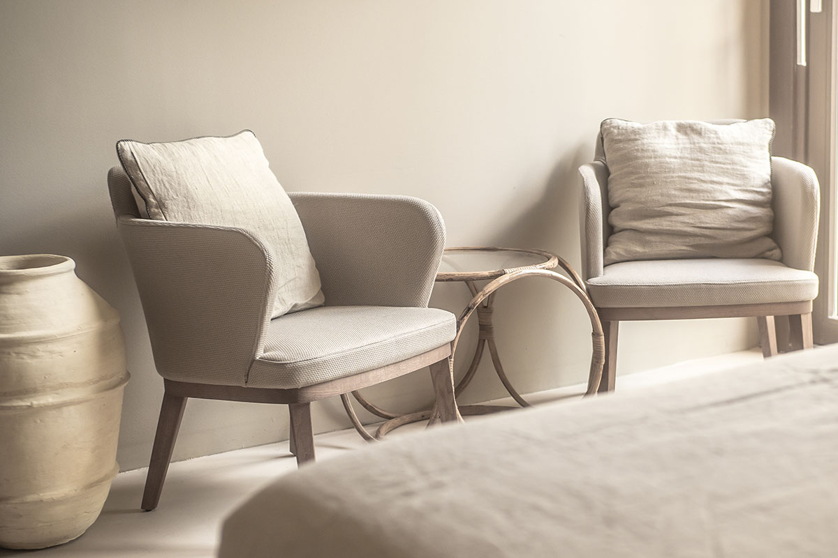 Zwei gemütliche Sessel mit Kissen, ein Naturholztisch und warme Lichtakzente im Zimmer Puro im Barefoot Hotel Mallorca.