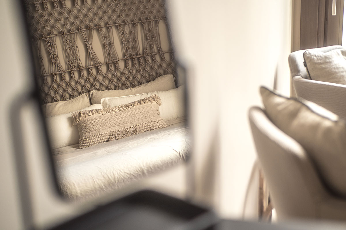 Spiegelreflexion des Hotelzimmers Puro mit Makramee-Bettkopfteil, beigen Kissen und natürlichen Materialien im Barefoot Hotel Mallorca.
