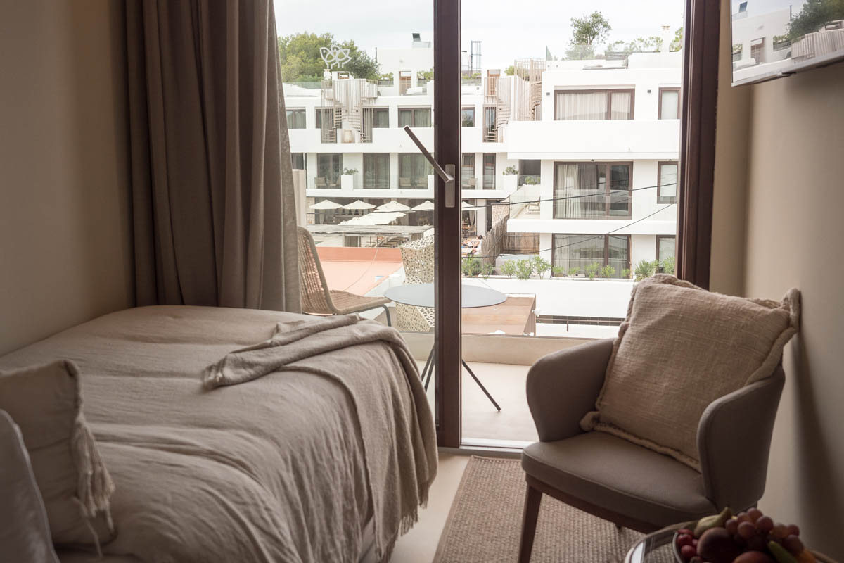 Zimmer Dormitorio im Barefoot Hotel Mallorca mit Einzelbett, Sessel und Balkon mit Blick auf die Hotelanlage.