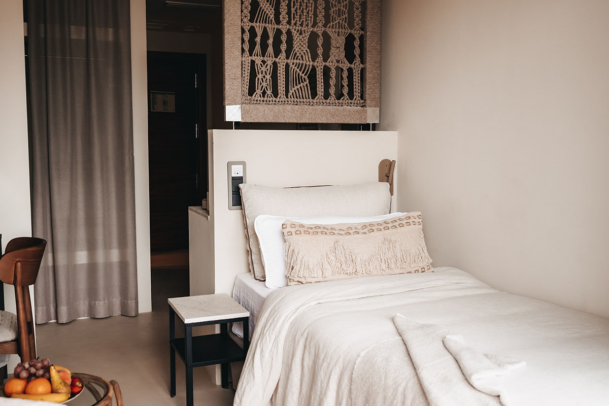 Modernes Zimmer Dormitorio im Barefoot Hotel Mallorca mit gemütlichem Einzelbett, weißen Textilien und Boho-Wandteppich.