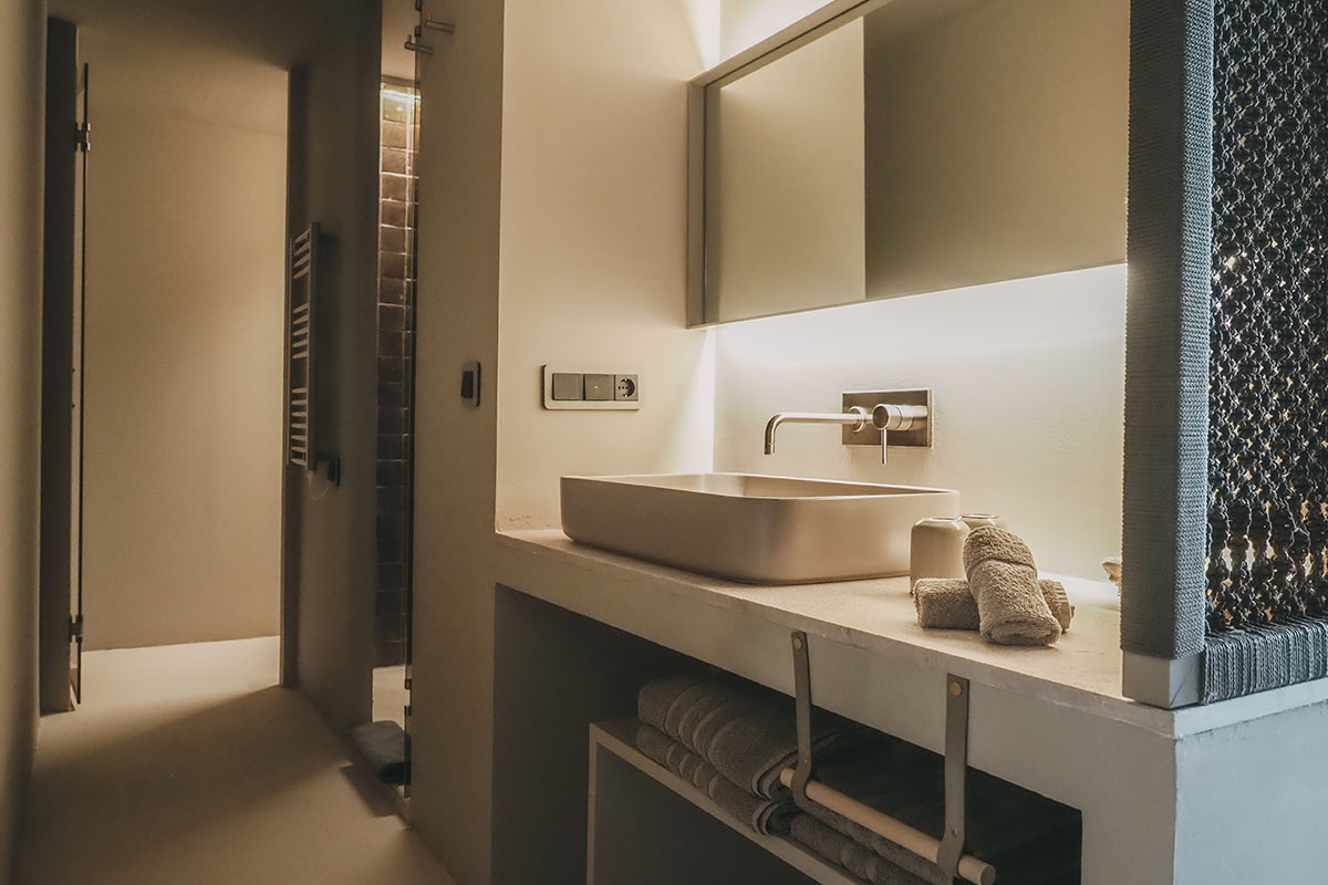 Moderno cuarto de baño en la habitación Pino del Hotel Barefoot Mallorca con lavabo de diseño e iluminación atmosférica.